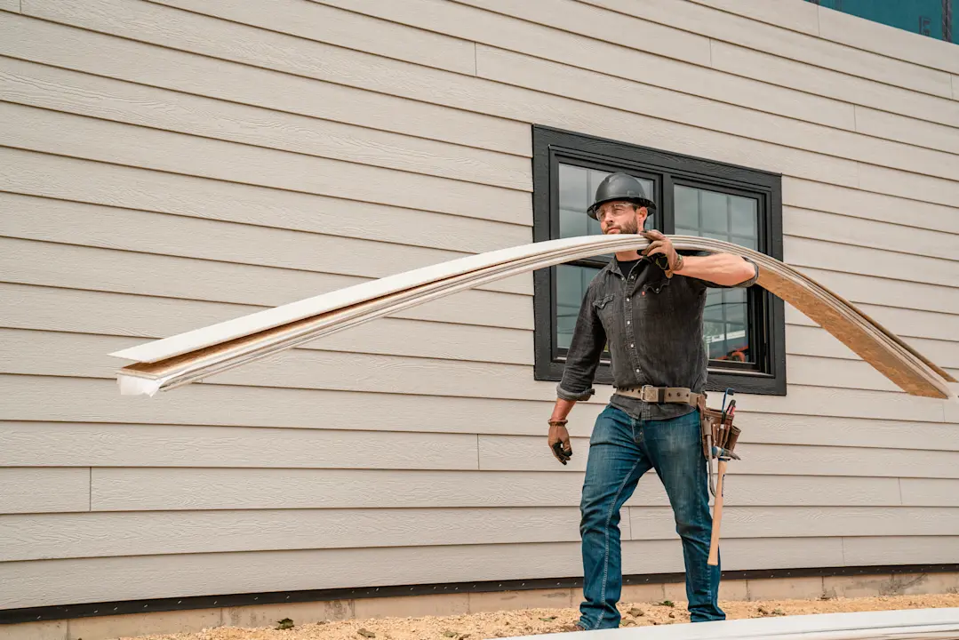 Siding installer carrying siding boards on a jobsite