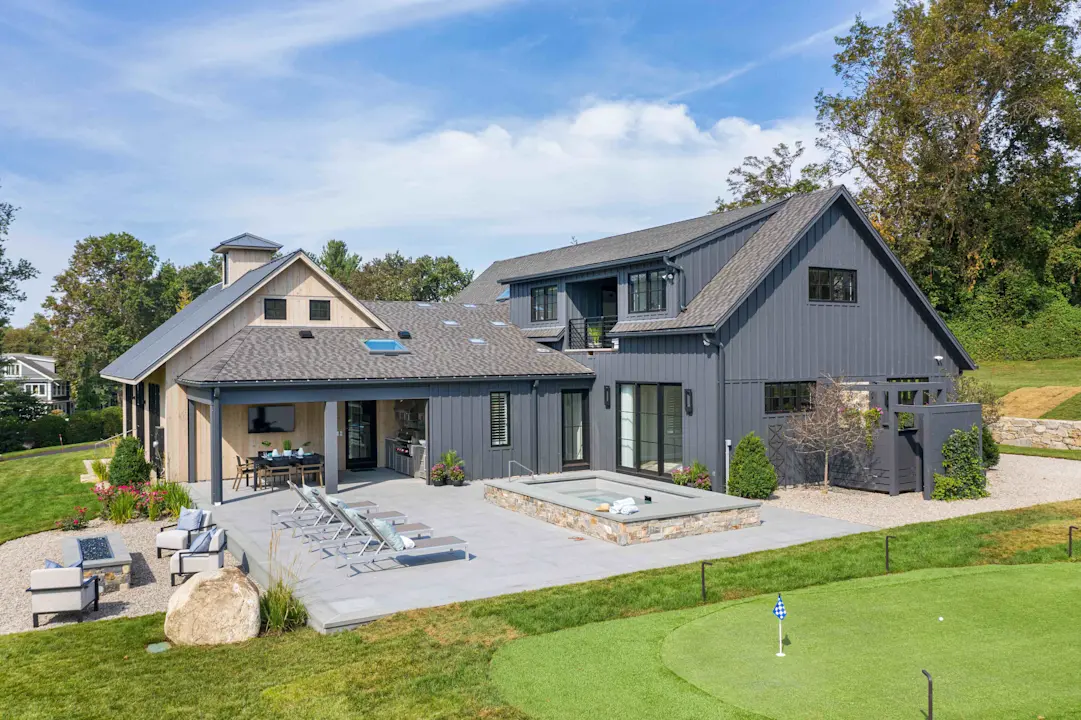 gary house with vertical siding and a small pool