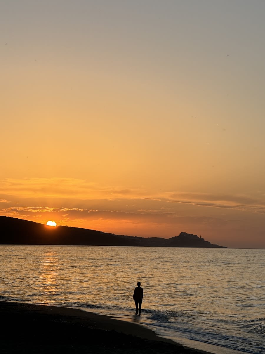 Zachód słońca na Sardynii jesienią na plaży Spiaggia San Pietro A Mare di Valledoria. W tle miasteczko Castelsardo.