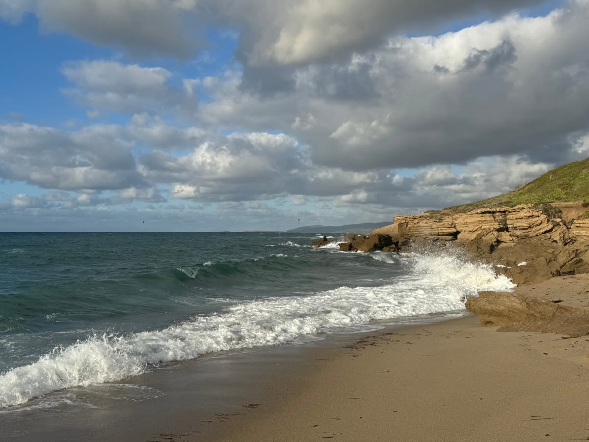 Plaża o nazwie di Maragnani w północnej części Sardynii, blisko Castelsardo i Valledorii. Dzień jest wietrzny, fale na morzu są widoczne.
