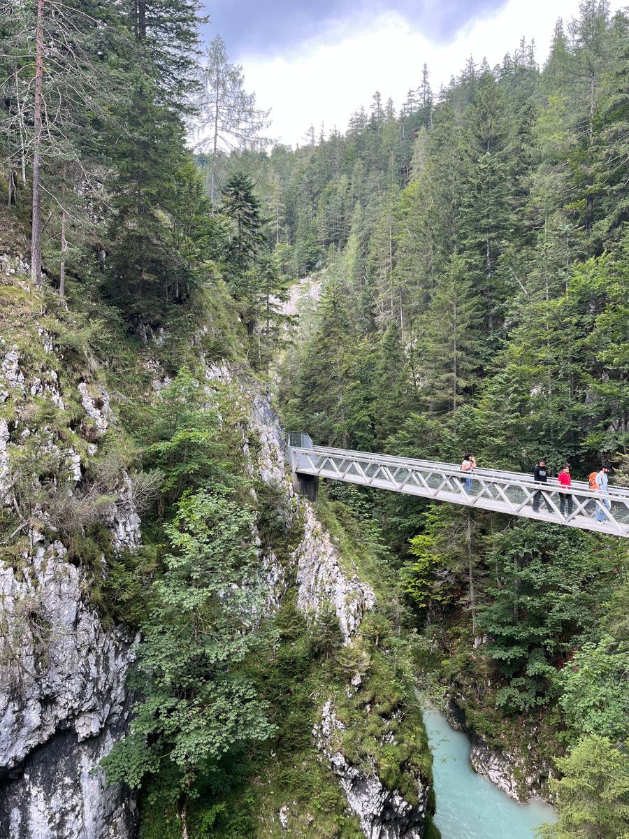 Na panoramicznym moście Panorama-Brücke w wąwozie Leutascher Geisterklamm pozują turyści. W dole płynie rzeka Leutascher Ache.