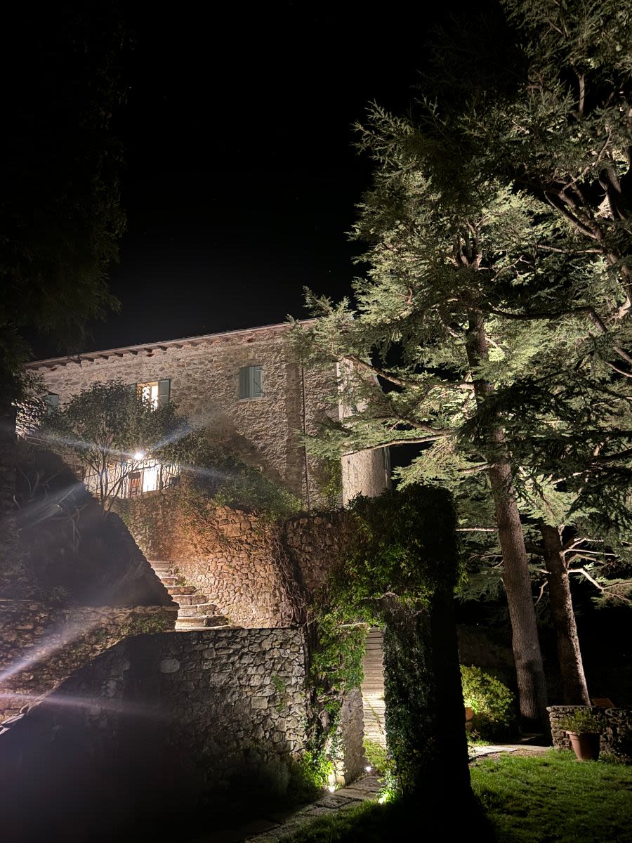 Fort La Rocca di Camporgiano wieczorem. Oświetlenie oświetla mury twierdzy i ogród otaczający twierdzę.