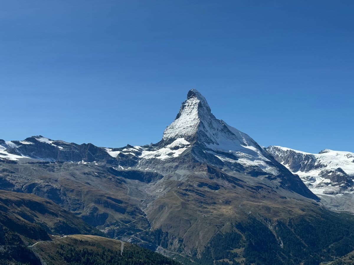 Zbliżenie na najsłynniejszą górę Szwajcarii - Matterhorn. Jest letni ciepły dzień. Wokół Matterhornu widoczne mniejsze szczyty.