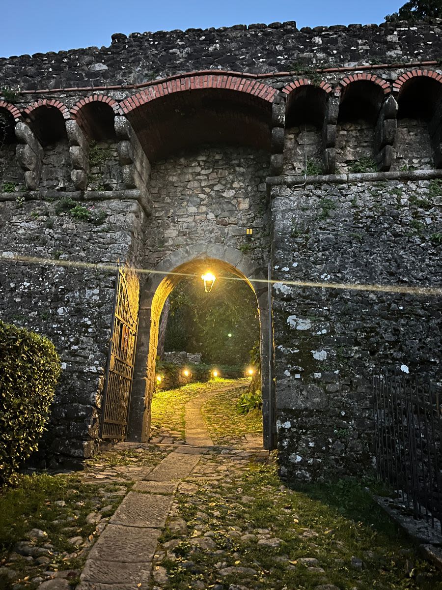 Wejście do La Rocca di Camporgiano. Brama do fortu jest otwarta. Światło oświeca kamienną drogę.