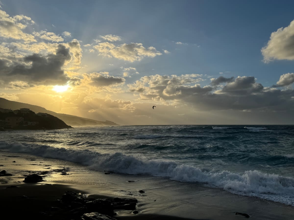 Plaża Spiaggia di Maragnani w prowincji Sassari na Sardynii. Jest wietrzny dzień, w morzu pływają kitesurferzy.