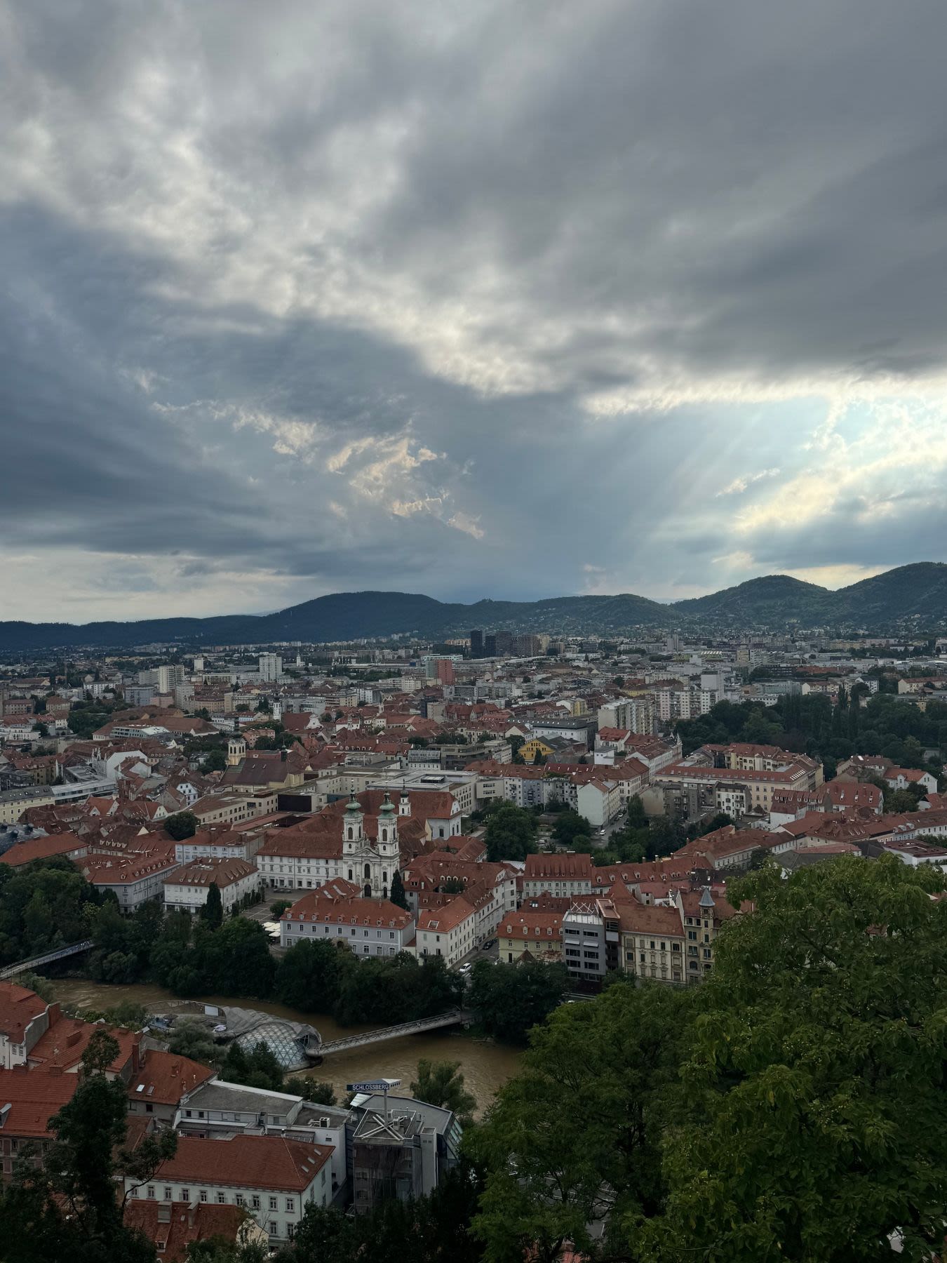 Widok na Graz ze wzgórza zamkowego Schlossberg. Wśród historycznej zabudowy miasta wyróżnia się sztuczna wyspa - Murinsel zbudowana na rzece Mur. 
