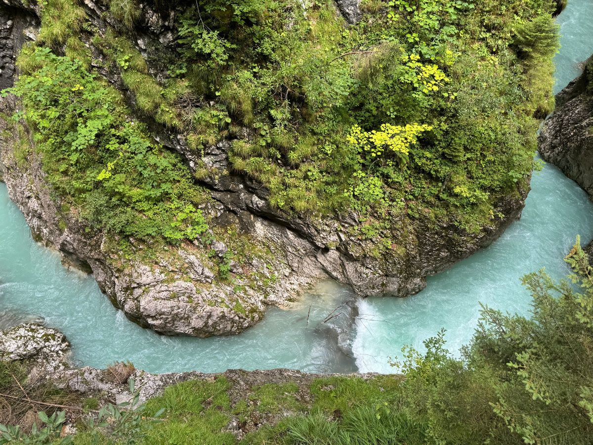 Na dnie wąwozu Leutascher Geisterklamm w Austrii płynie rzeka Leutascher Ache. Woda jest w kolorze niebieskim. Zbocza wąwozu porasta roślinność.