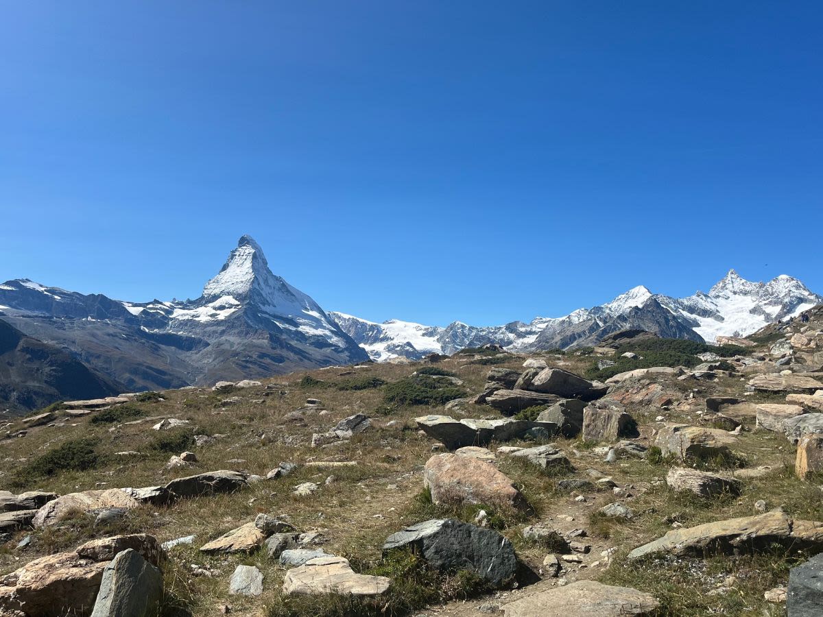 Najsłynniejsza góra Szwajcarii - Matterhorn na tle błękitnego bezchmurnego nieba. Górski krajobraz z alpejskimi szczytami. Na pierwszym planie duże kamienie.