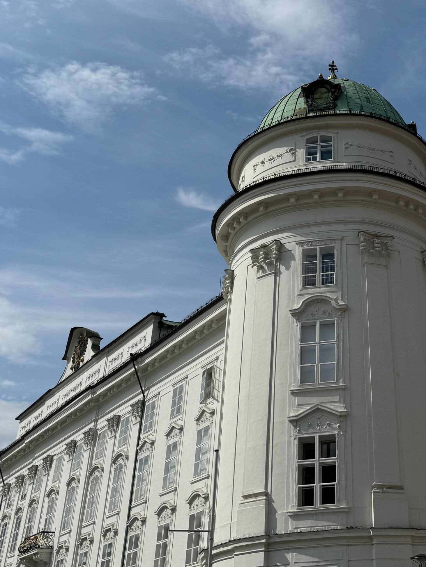 Fragment Hofburg Innsbruck - pałacu cesarskiego. Okna są bogato zdobione, dach w kolorze pastelowej zieleni.