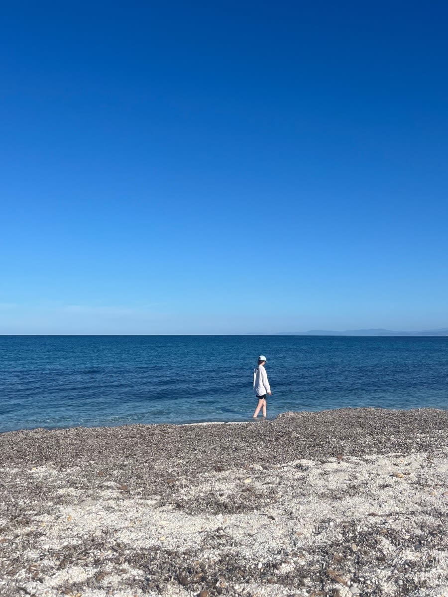 Plaża Spiaggia Pazzona w północnej Sardynii w październiku. Plaża pokryta jest białymi przyjemnymi w dotyku kamyczkami. Woda w morzu jest bardzo przejrzysta.