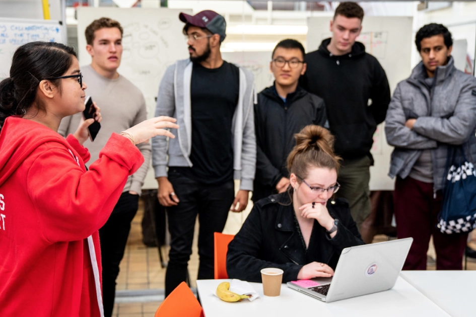 Person working on a laptop with 6 people watching