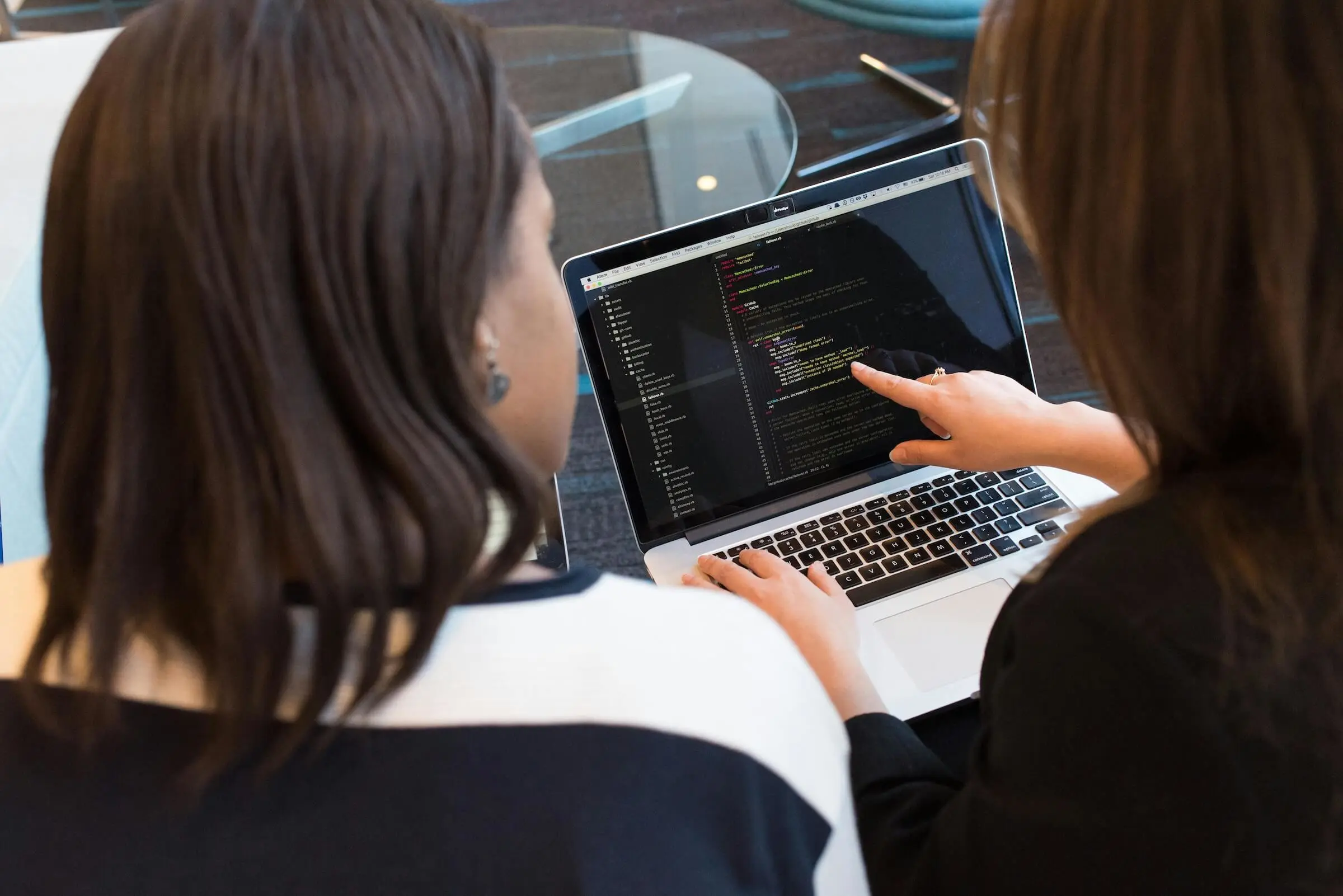 Two people looking at code on a laptop