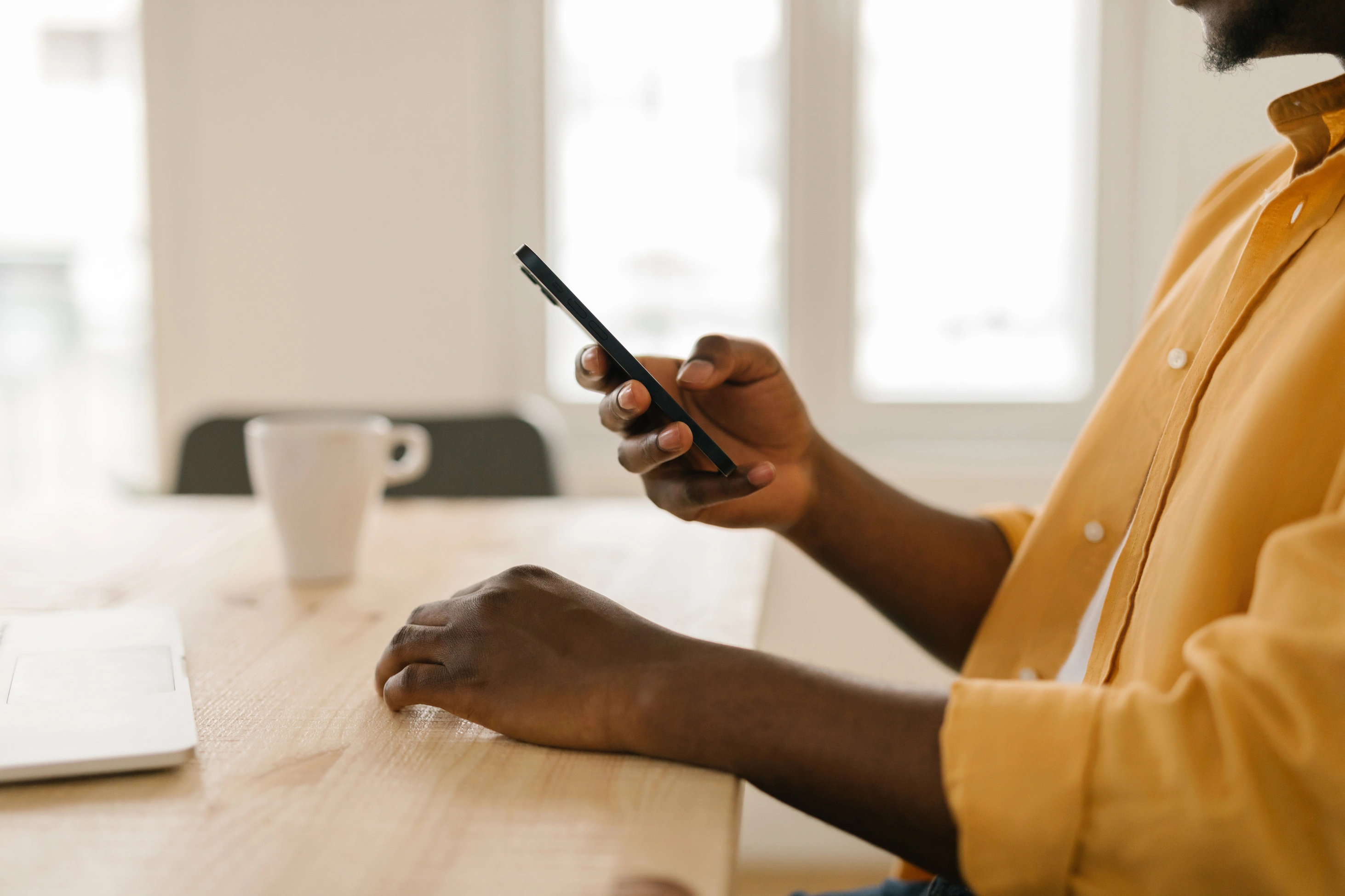 Nahaufnahme eines unkenntlichen Schwarzen Mannes, der sein Smartphone nutzt.