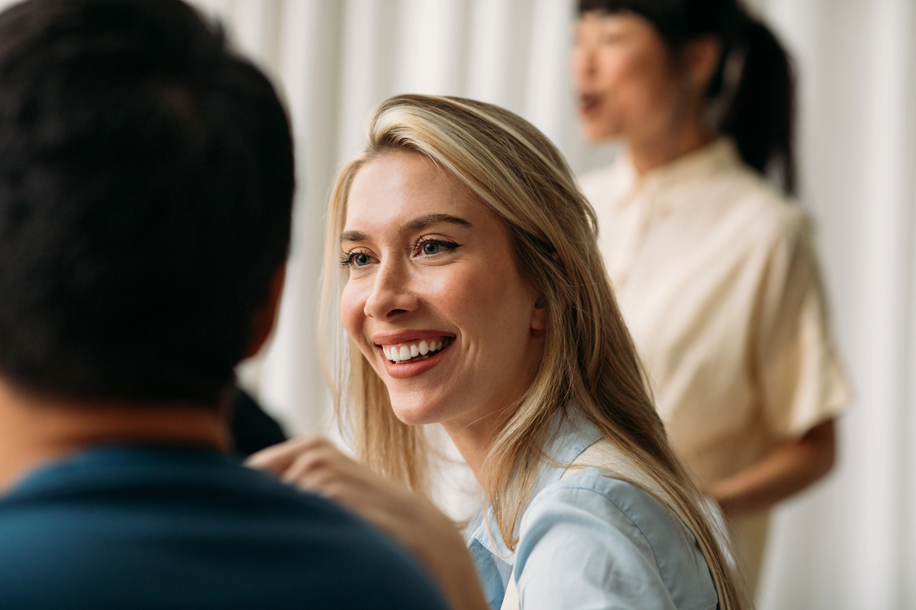 Eine blonde Frau lacht während eines Meetings.