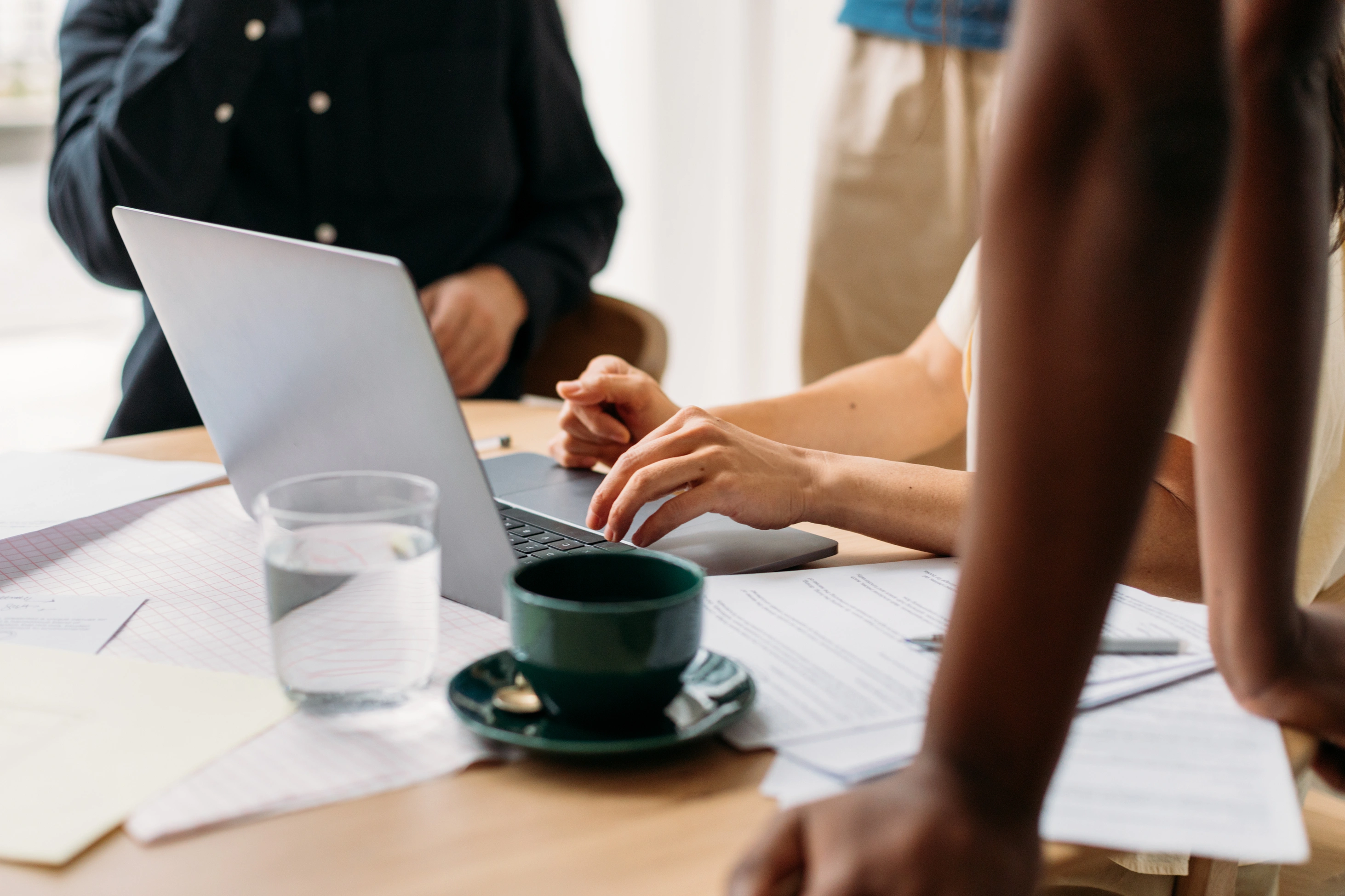 Mehrere Personen, deren Gesichter nicht zu erkennen sind, sitzen im Büro zusammen und besprechen sich.