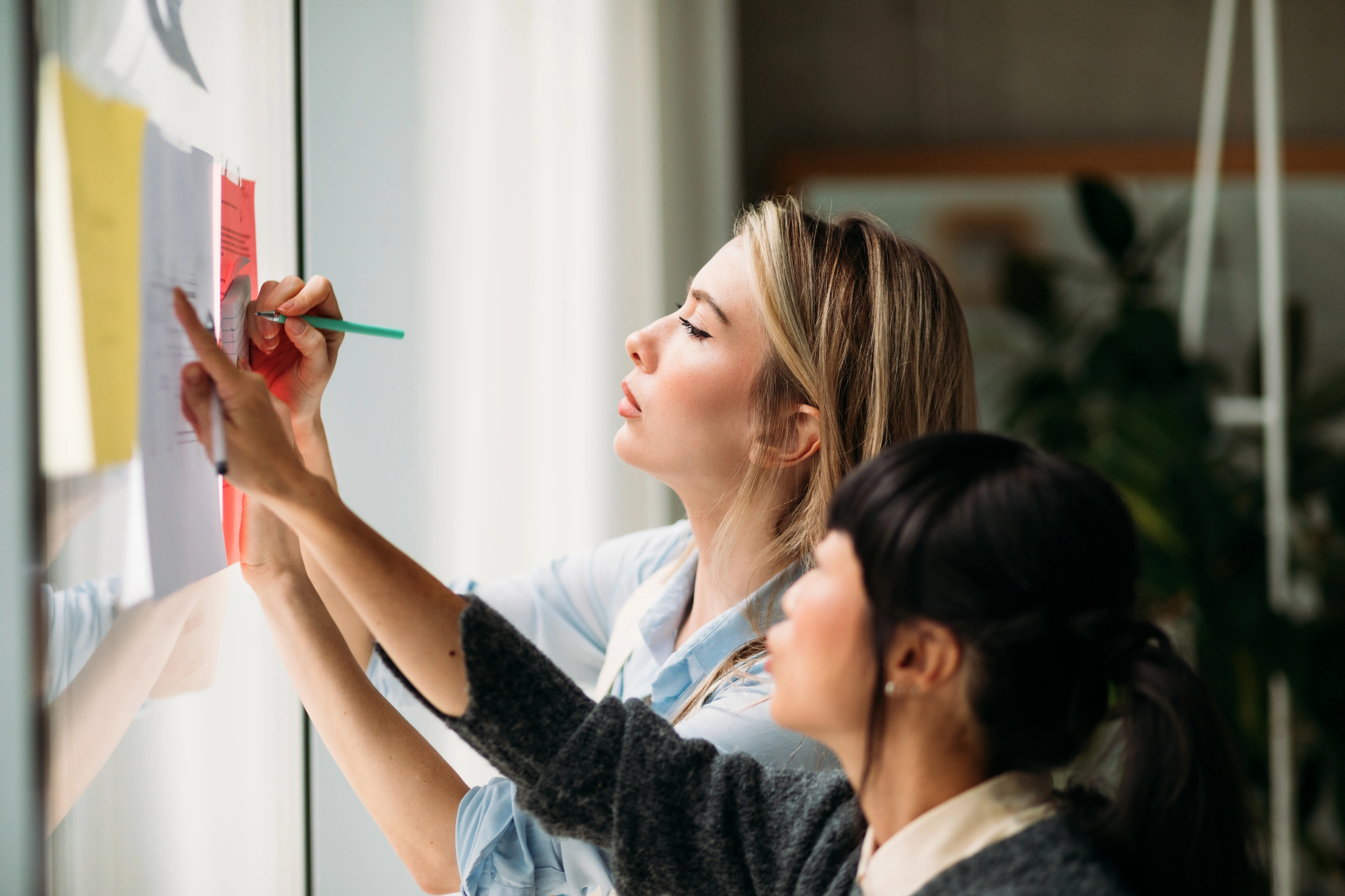 Frauen stehen zusammen und arbeiten an Dokumenten.