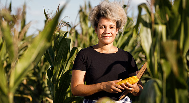 Female farmer holding corn ear in corn field