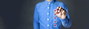A person in a blue shirt marking checkboxes with red check marks on a transparent virtual screen, representing a completed checklist.