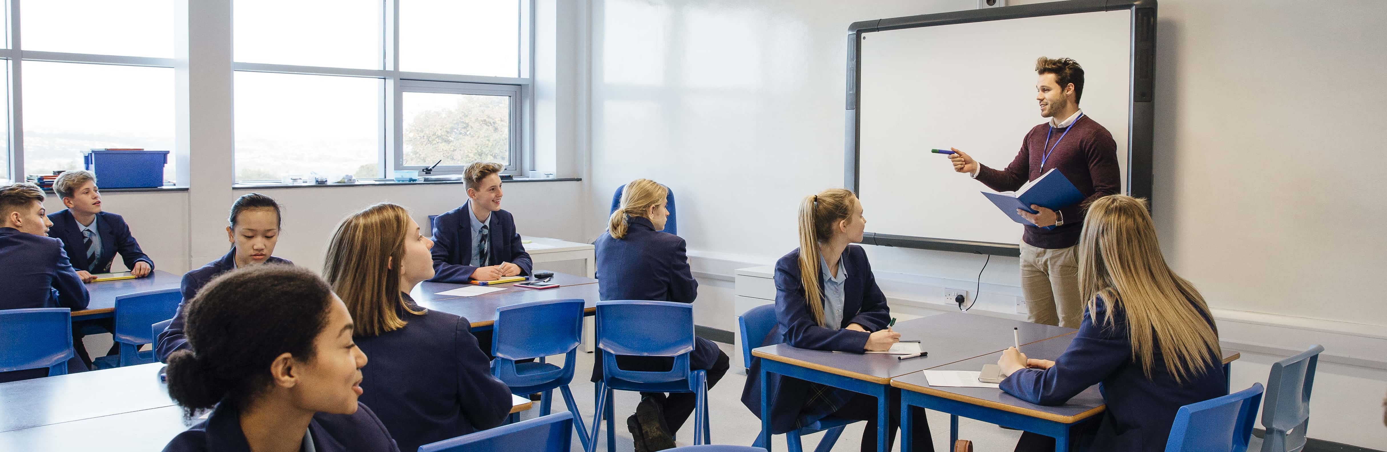 Male teacher is teaching a group of teenagers in a high school.