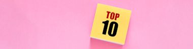 A yellow notepad with TOP 10 written in bold red and black letters sits on a pink background.