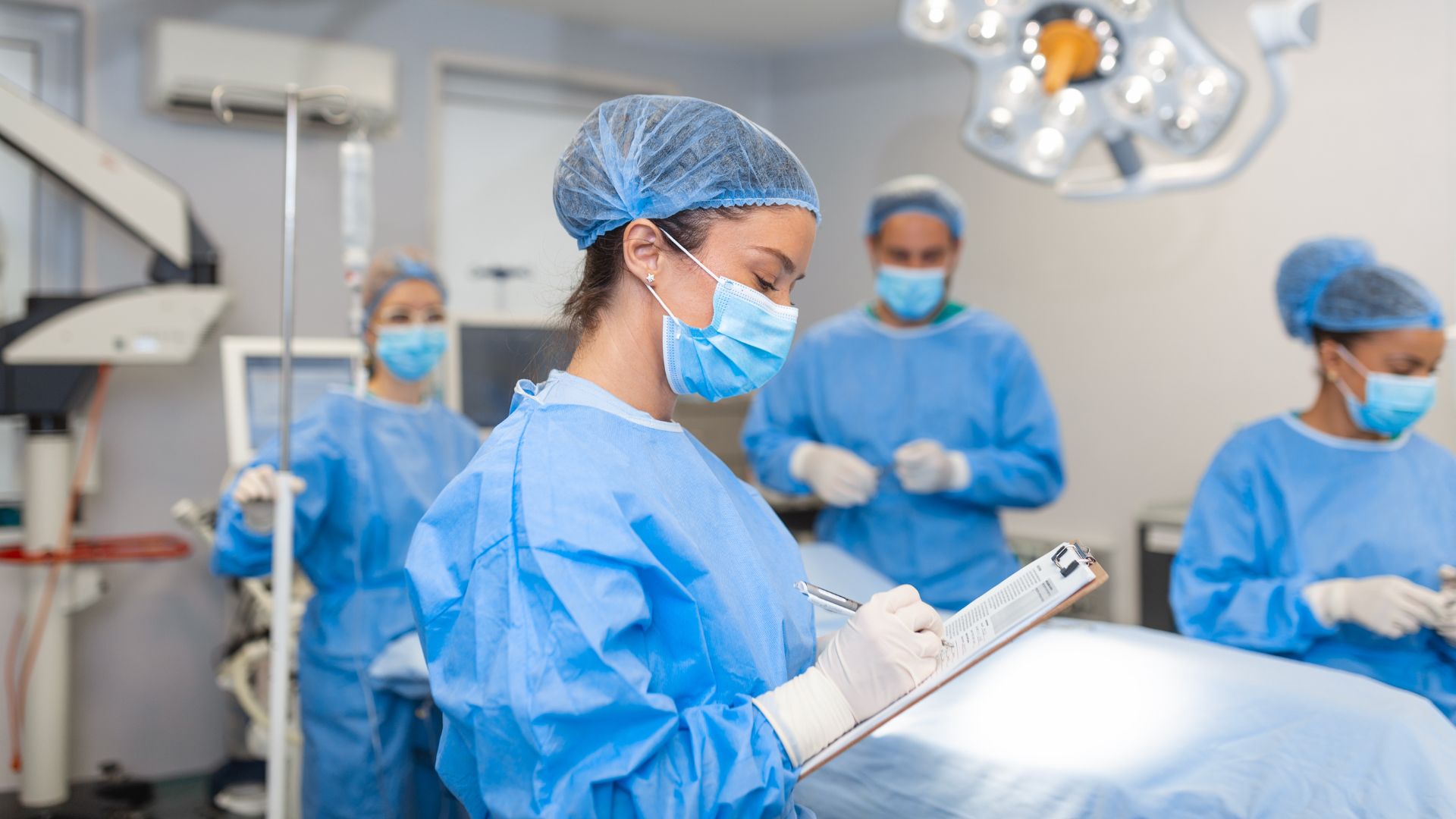 An anesthesiologist holding a patient's chart in the operating room.