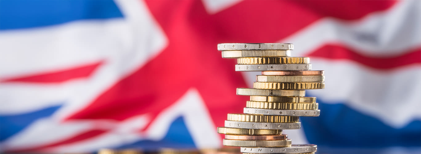 Pile of coins against a UK flag