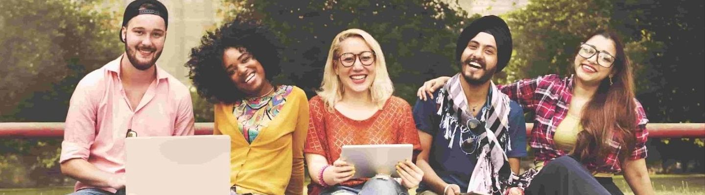 A group of happy diverse students sitting together on a bench.