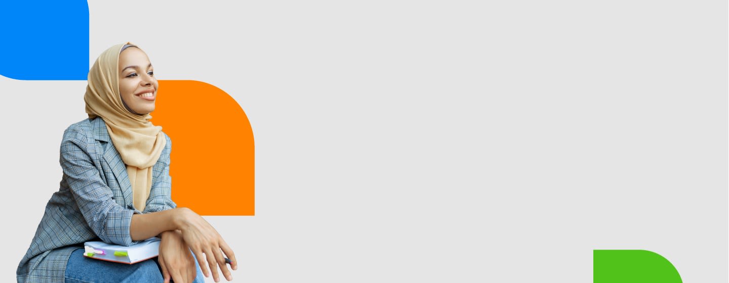 Smiling young woman in a hijab holding books, seated against a colorful abstract background