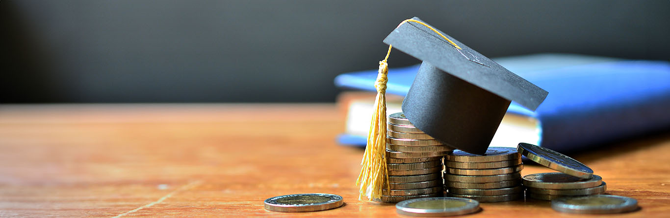 Graduation cap sitting on a pile of coins representing scholarship money