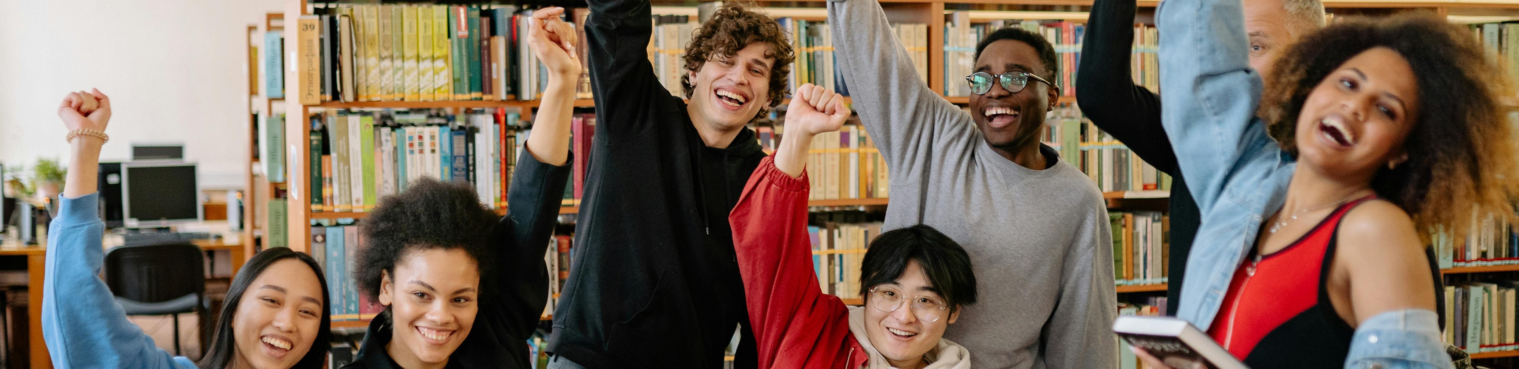Happy group of students raise their hands