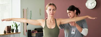 A person is undergoing a physical therapy session with a physiotherapist assisting
