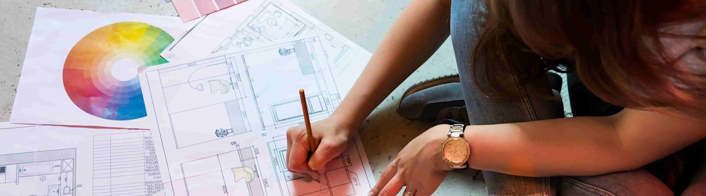 A student sitting on the floor and working on blueprints