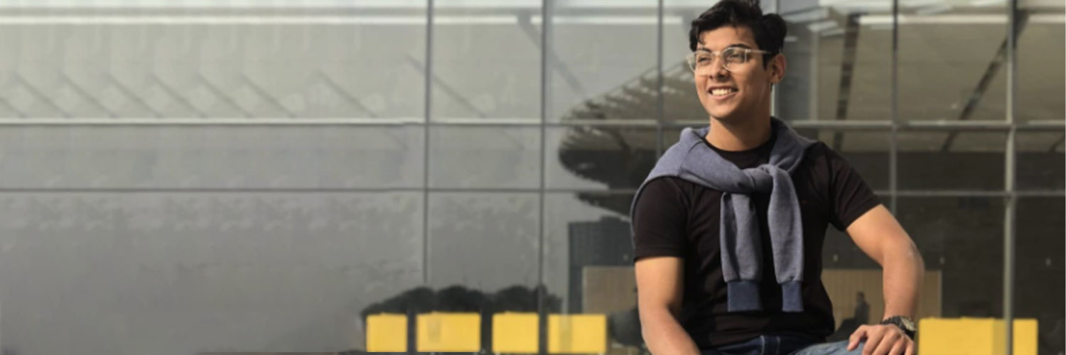 Raiyan Hasan looks off to the side in front of a building