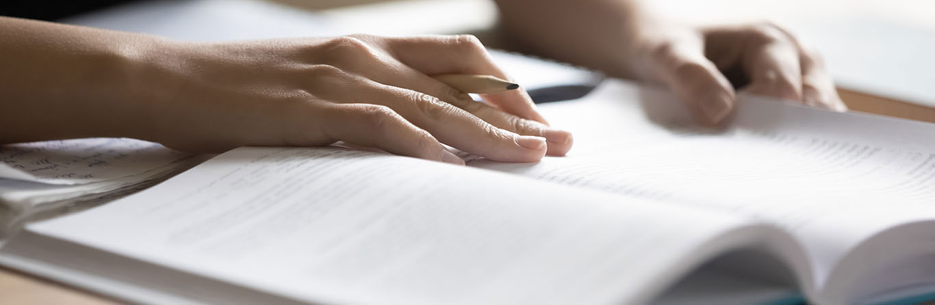 a woman holding a pen while reading a book