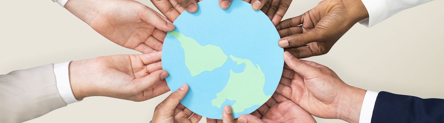 Multiple sets of hands holding a paper cutting of a earth