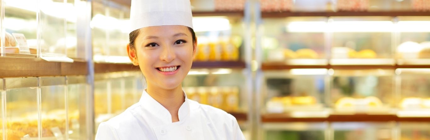 A bakery cook is standing in the bakery
