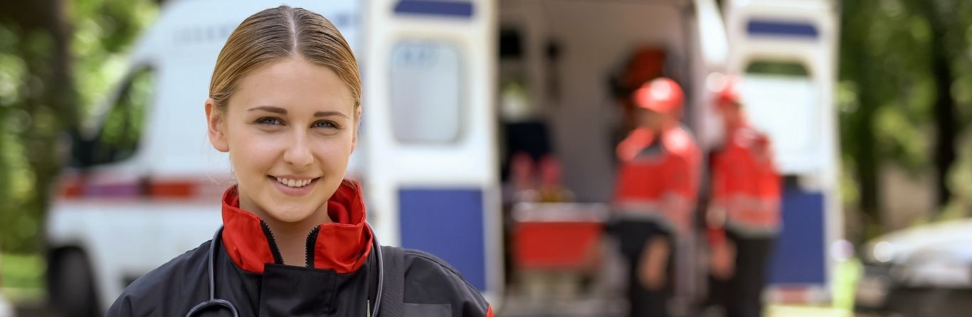 A paramedical graduate is standing beside an ambulance