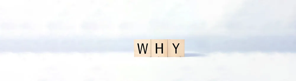 Three wooden tiles with the letters W, H, and Y are arranged in a row to spell WHY against a white, softly blurred background.