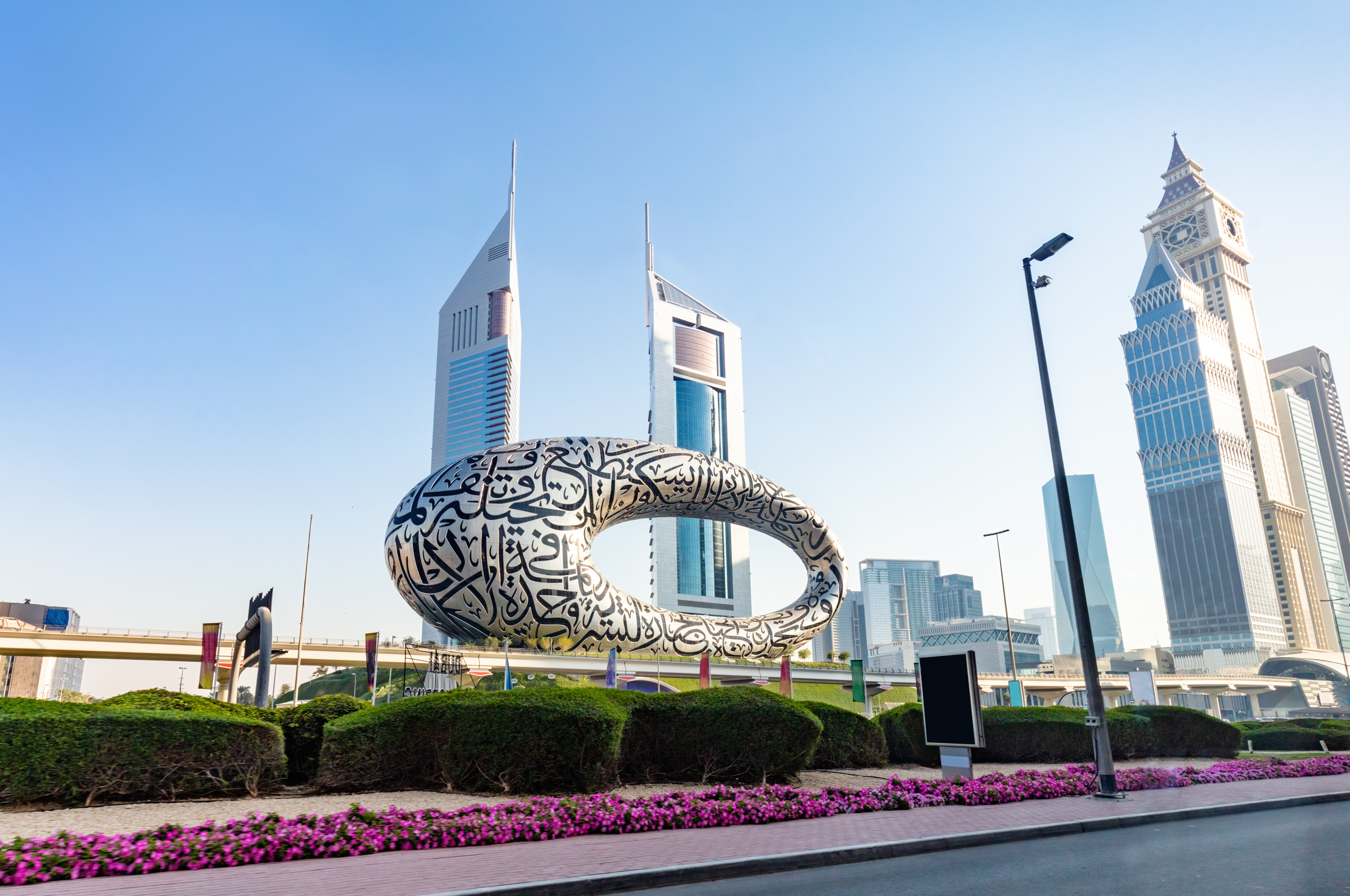 Photograph of the Museum of the Future, set against a backdrop of iconic skyscrapers including Emirates Towers and Al Yaqoub Tower.