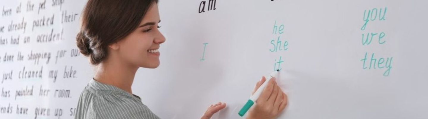 A female student writing English with a marker on a white board