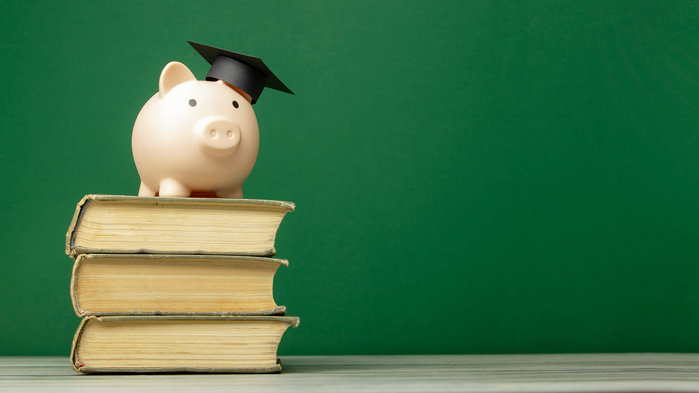 Tuition concept, piggy bank wearing a grad cap on a stack of books against a green background