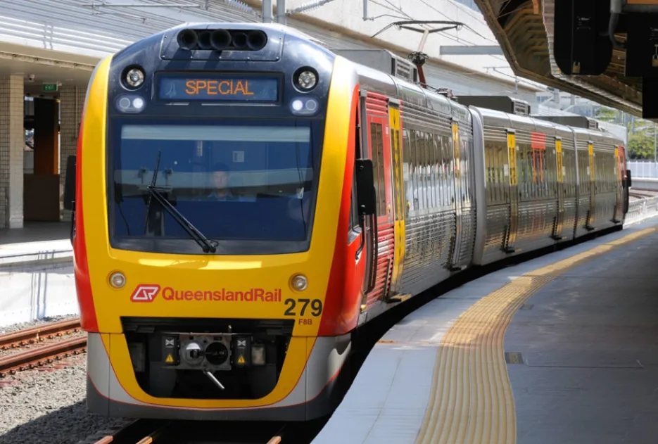 Queensland Rail special service train in red and yellow livery stopped at curved platform, displaying "SPECIAL" on digital sign