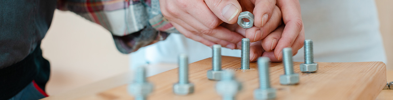 Closeup of man in occupational therapy screwing nut on bolt