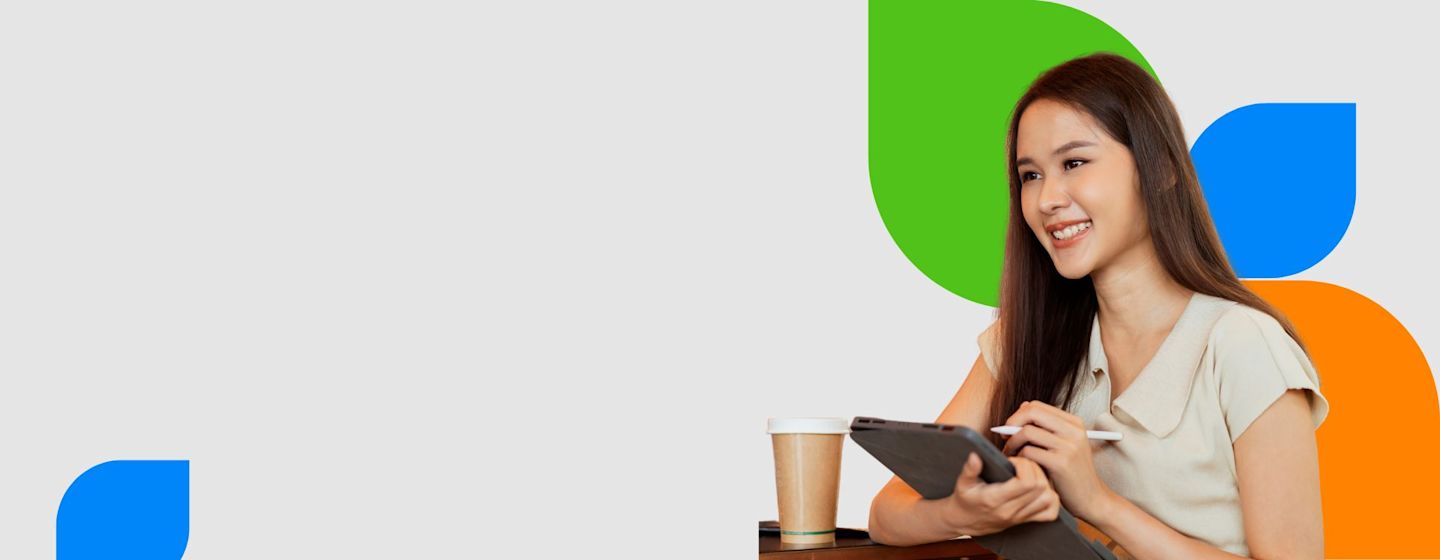 A person sits at a table holding a tablet, with a coffee cup beside them and colorful abstract shapes in the background