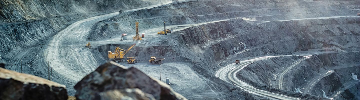 Trucks and excavators at work in an open pit for gold mining