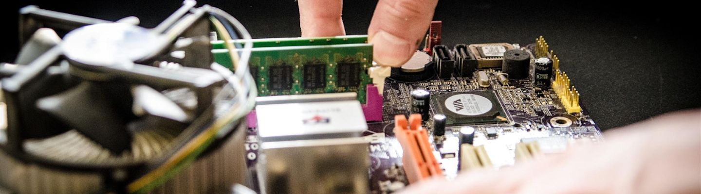 Close-up of hands repairing computer hardware, working on a circuit board with various electronic components visible
