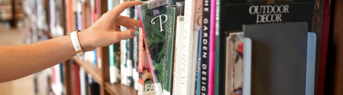 A picture of a girl's hand taking book from a library shelf