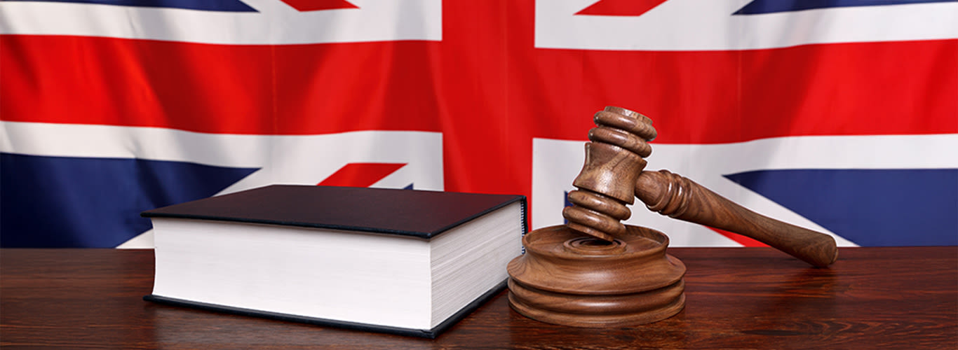 Book and gavel on a wooden desk, background UK flag