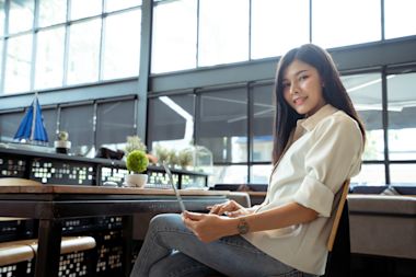portrait-smiling-young-woman-using-laptop-while-sitting-table