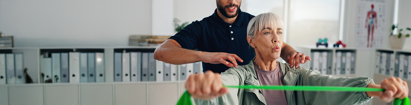Physiotherapist helps a client using a band for stretching